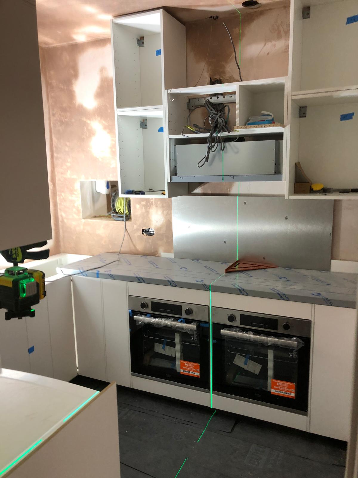 Kitchen during installation with exposed wiring and unfinished cabinets