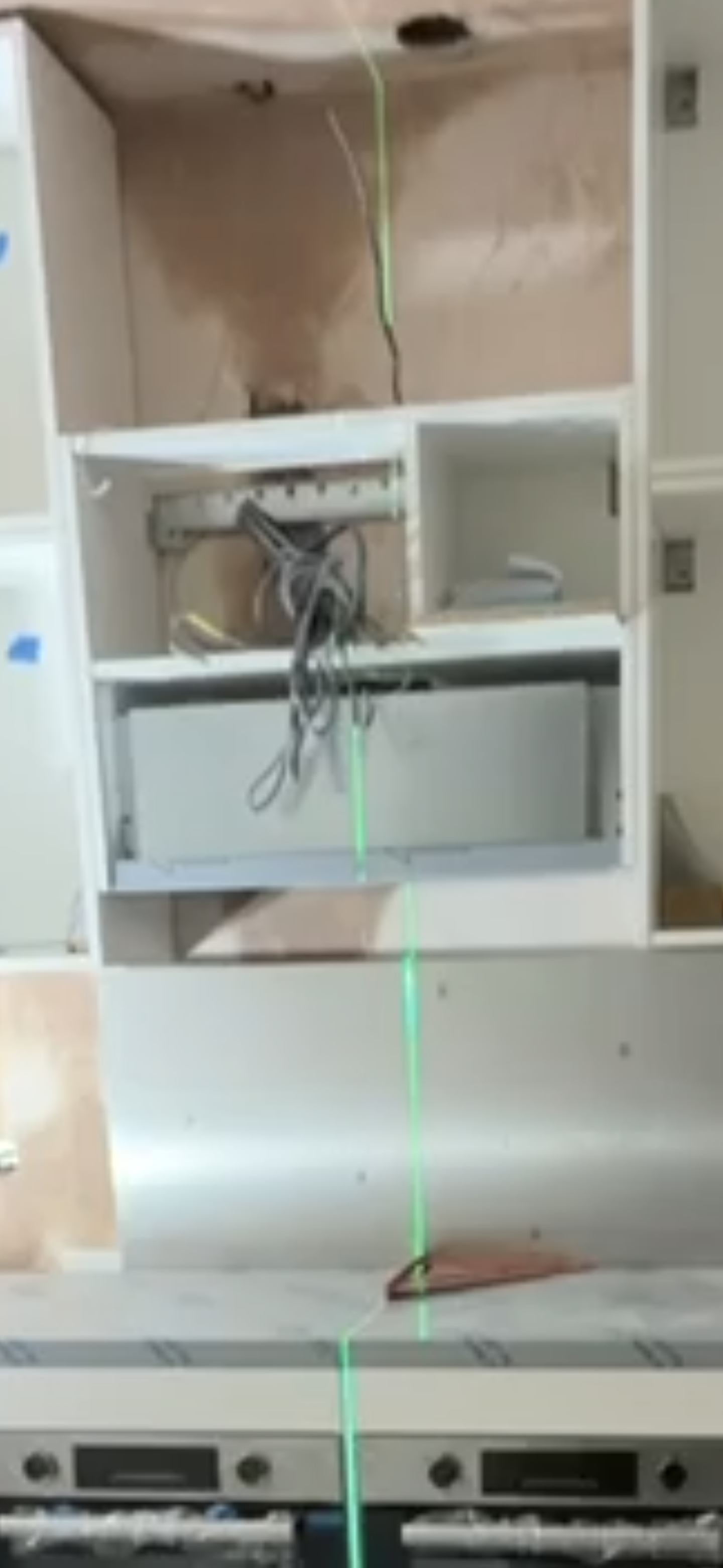 Kitchen cabinet with exposed appliance wiring before completion